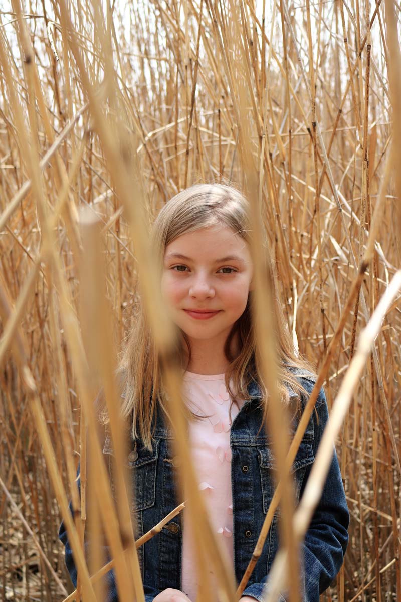 Young girl standing amongst dried plants