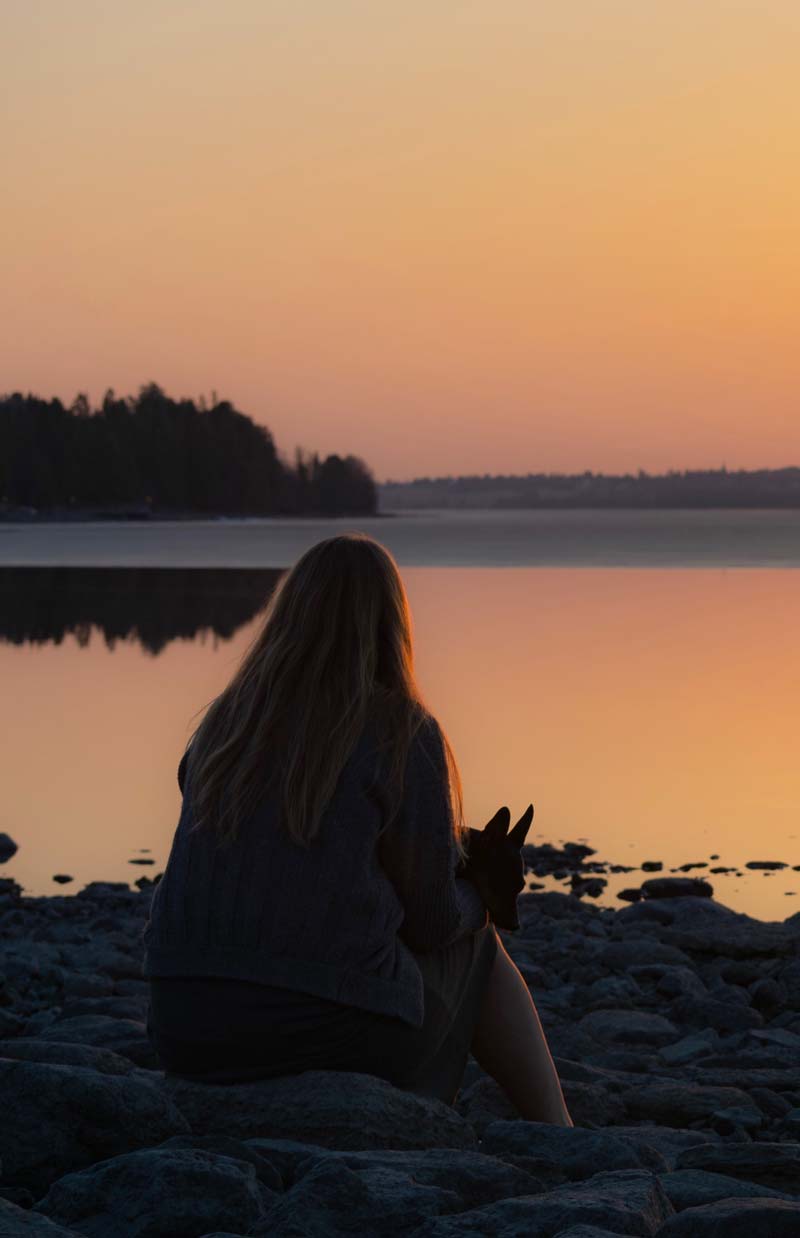 Rear view silhouette of a woman sitting beside a lake