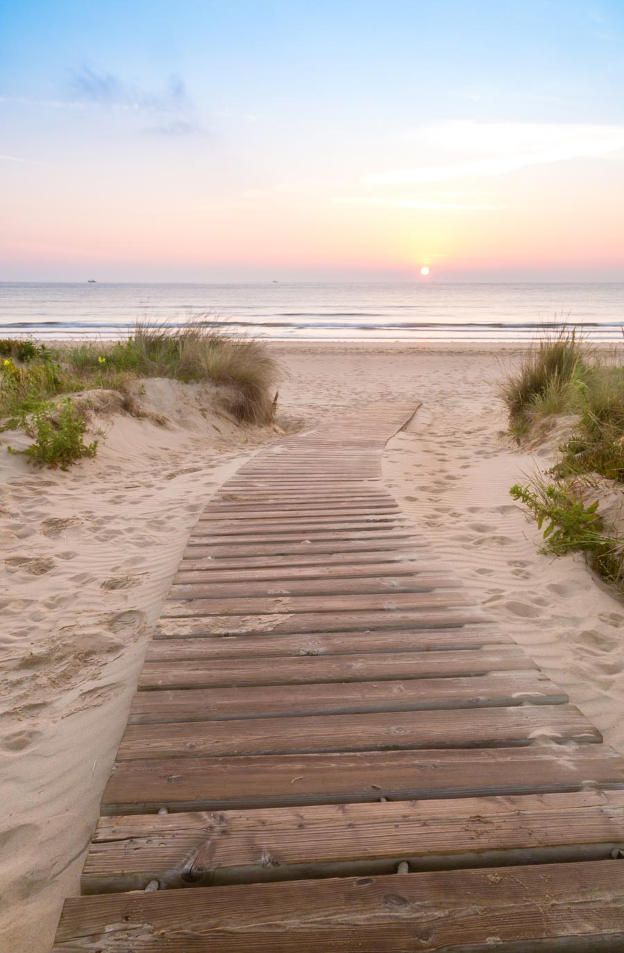 Wooden walkway entering beach with sunrise